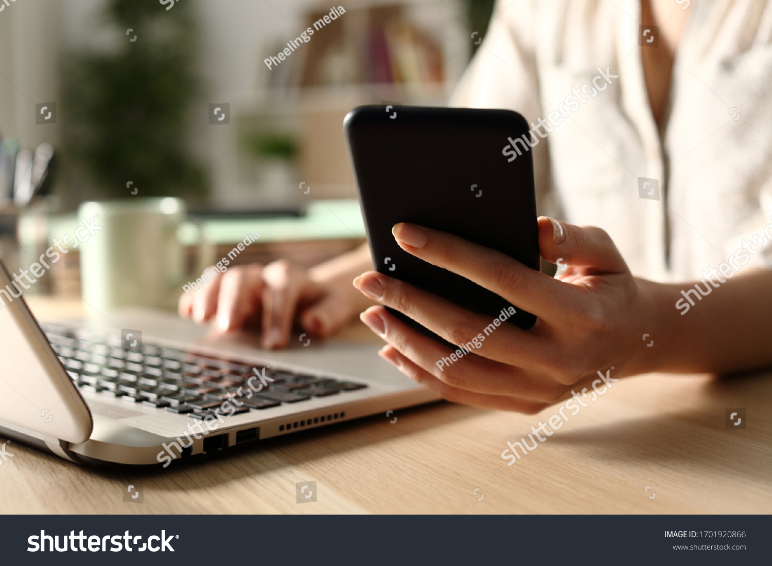 Close up of woman hands using laptop checking smart phone at night at home #1701920866