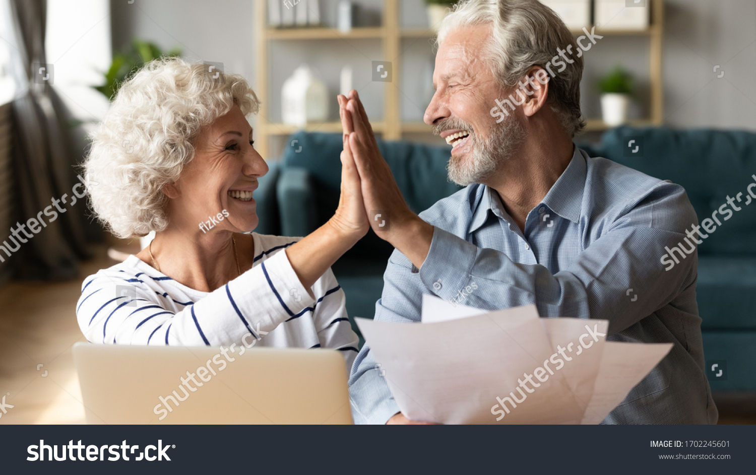 Excited older couple giving high five, mature family celebrating success, checking or paying domestic bills, planning budget, smiling mature man holding financial documents, reading good news #1702245601