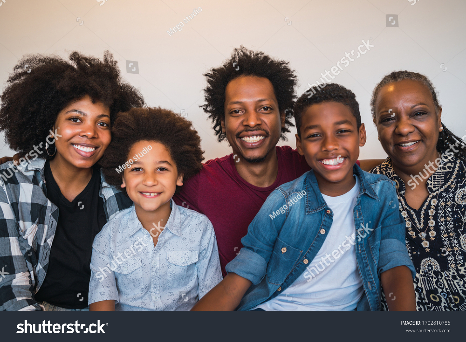 Portrait of african american multigenerational family looking at camera while sitting on sofa couch at home. Family and lifestyle concept. #1702810786