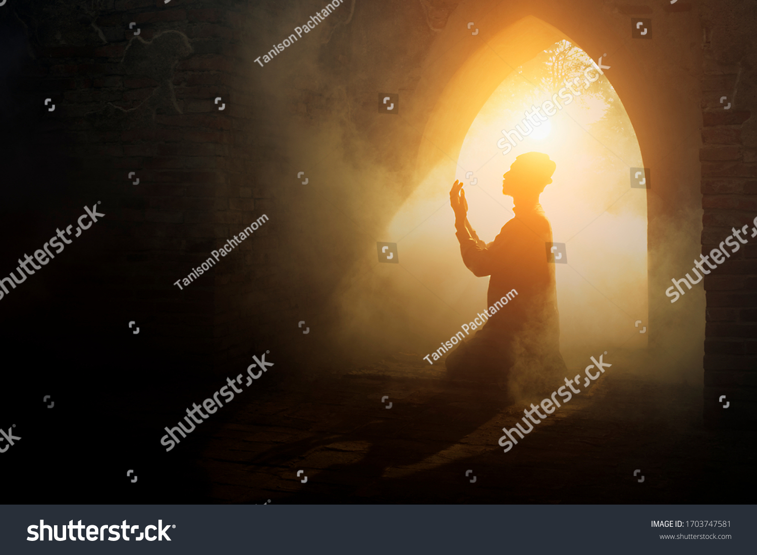 Silhouette of muslim man having worship and praying for fasting and Eid of Islam culture in old mosque with lighting and smoke background                                   #1703747581