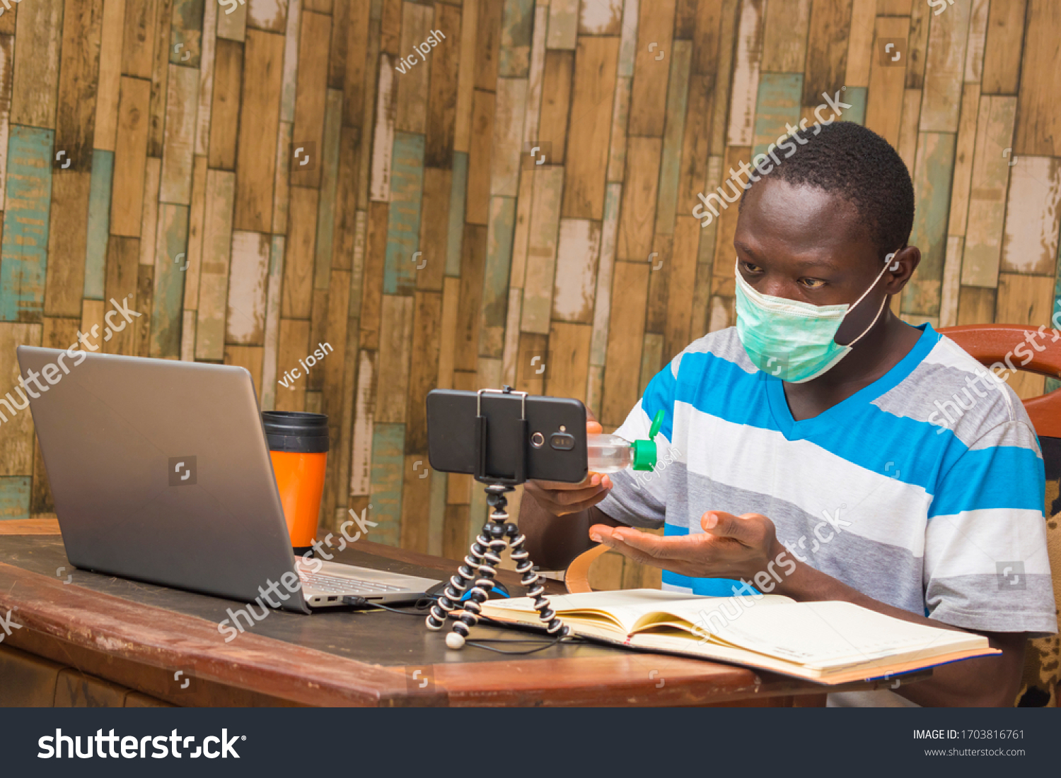 young african doctor wearing face mask isolated himself indoor carrying out research and making a video call #1703816761