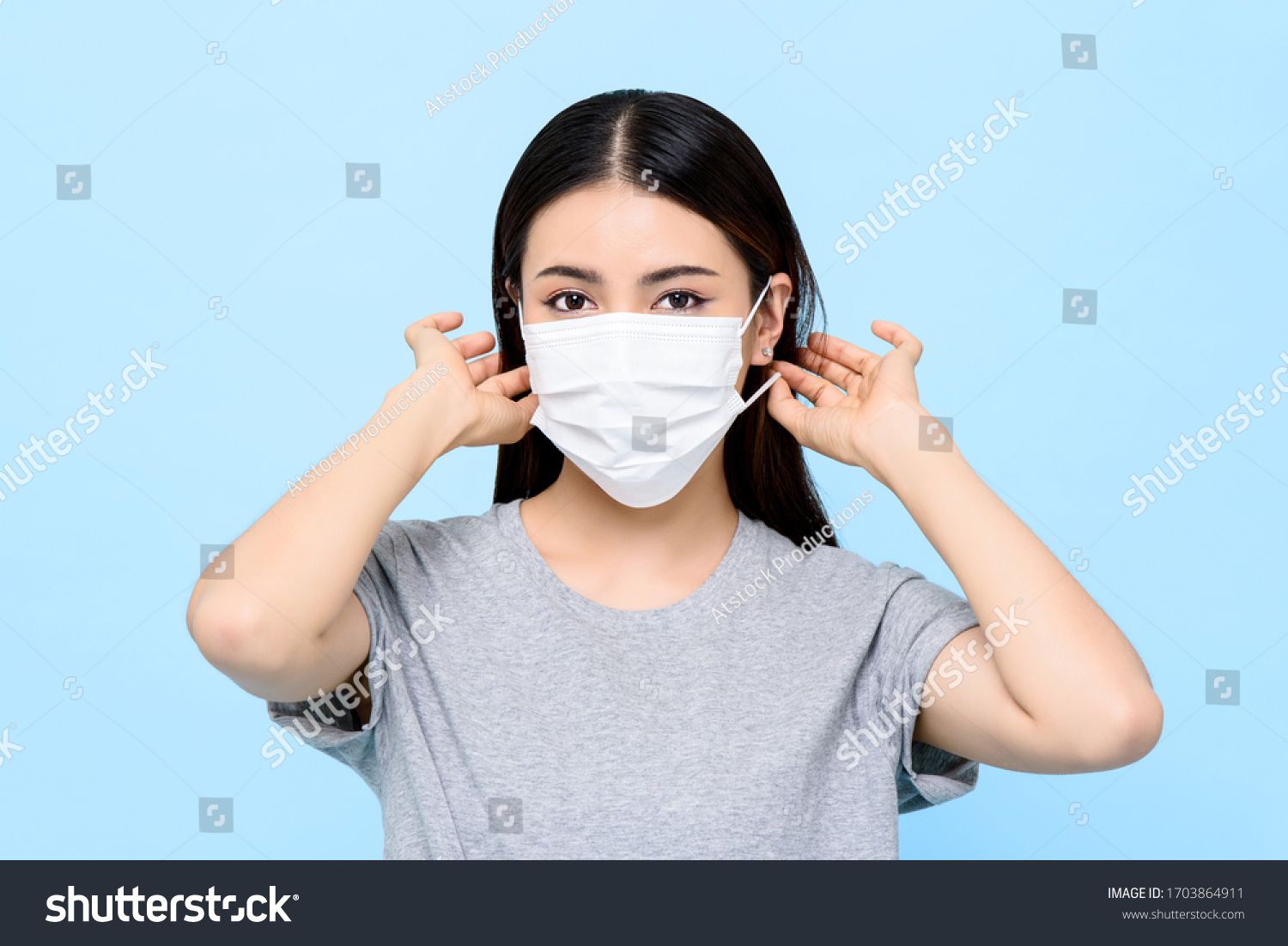 Asian woman wearing medical face mask isolated on light blue background #1703864911