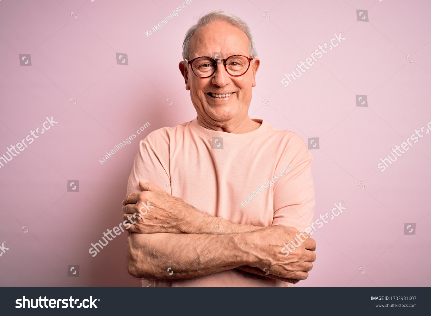 Grey haired senior man wearing glasses standing over pink isolated background happy face smiling with crossed arms looking at the camera. Positive person. #1703931607