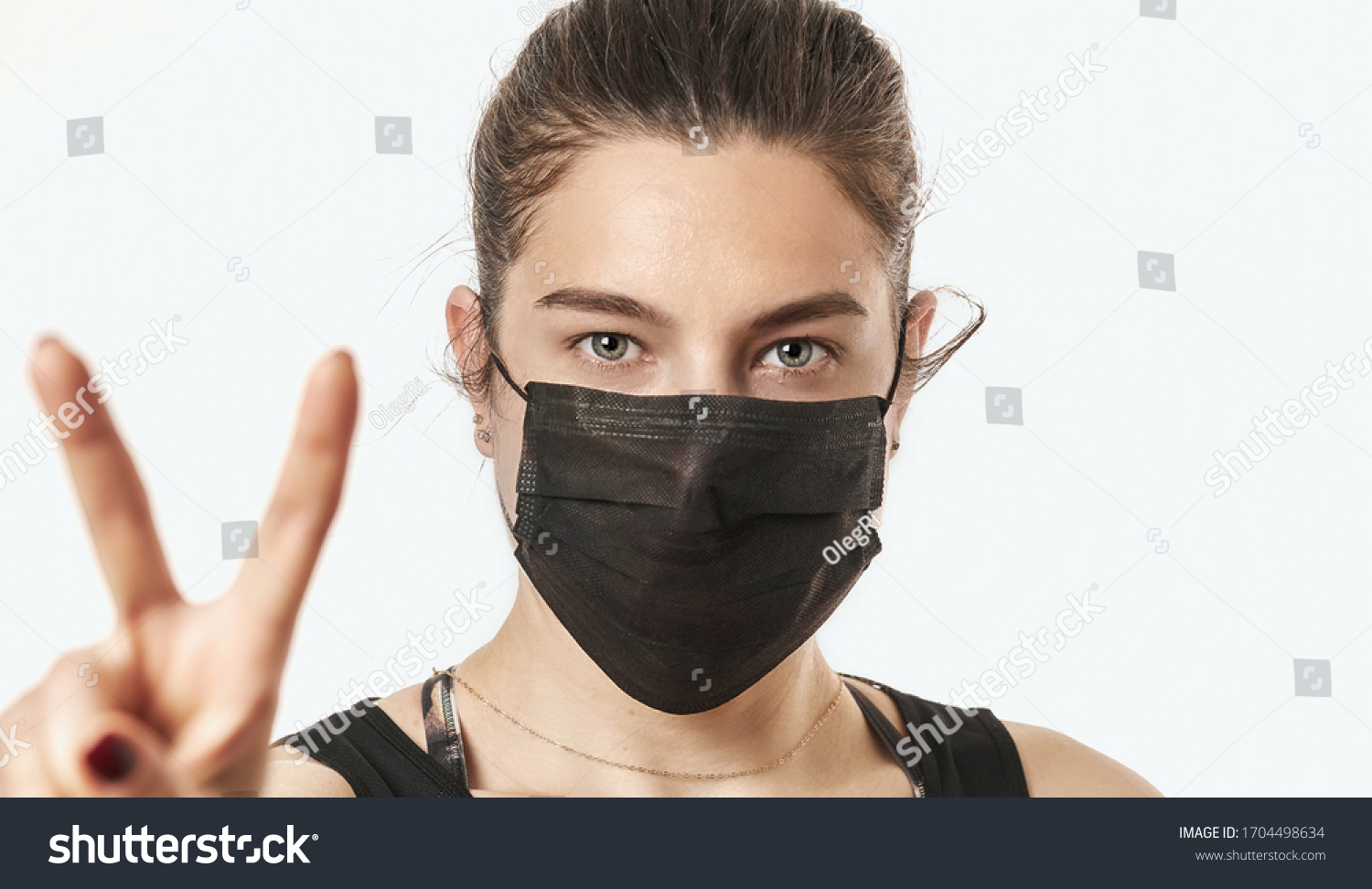 A close-up portrait of a pretty female wearing a surgical mask isolated on a white background #1704498634