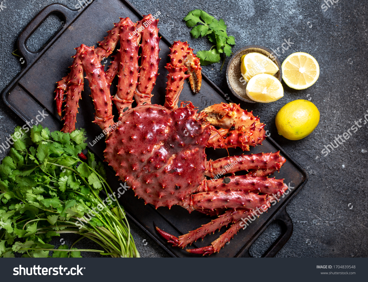 King Crab with lemon and cilantro on black background. Top view. #1704839548