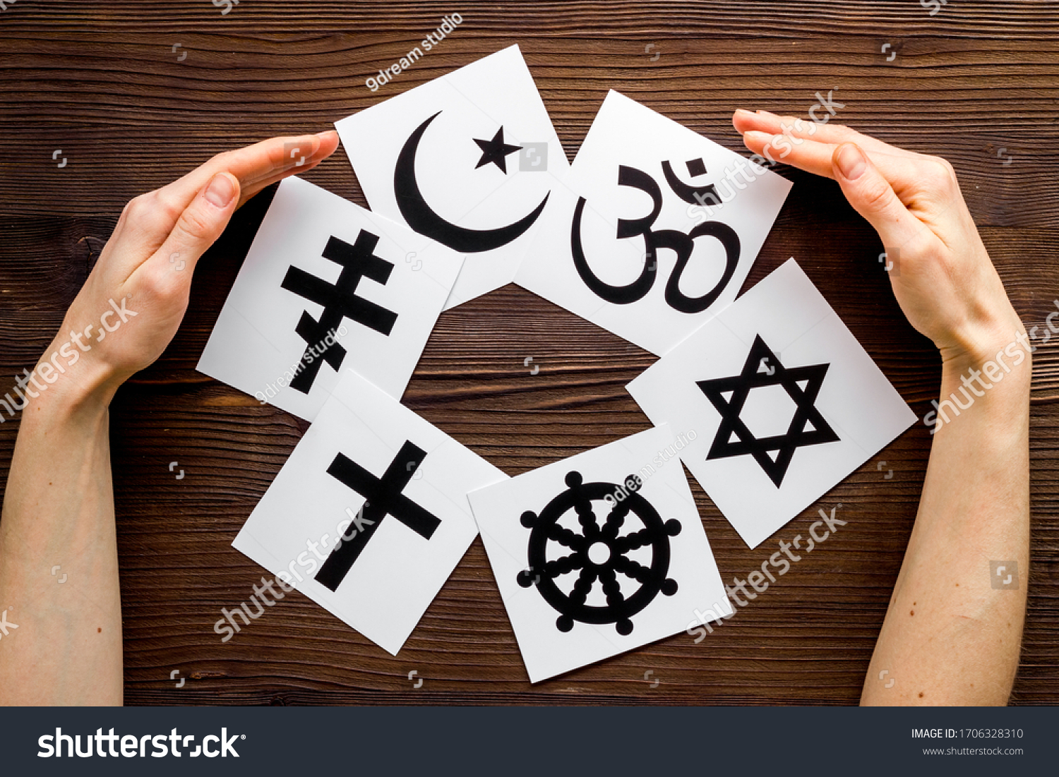 World religions concept. Hands hugs Christianity, Catholicism, Buddhism, Judaism, Islam symbols on wooden background top view #1706328310