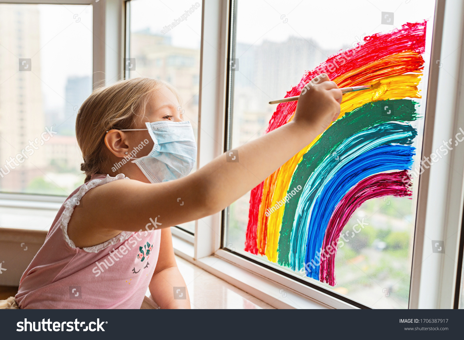 Kid painting rainbow during Covid-19 quarantine at home. Girl near window. Stay at home Social media campaign for coronavirus prevention, let's all be well, hope during coronavirus pandemic concept #1706387917