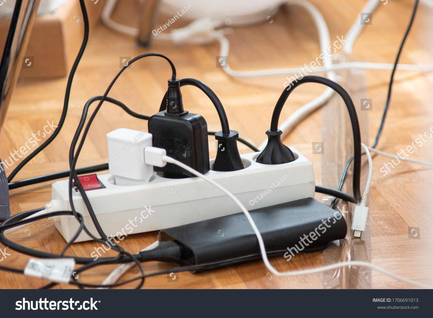 Messy outlet power extension cord on an apartment floor with various charging devices plugged in 2020 #1706691013