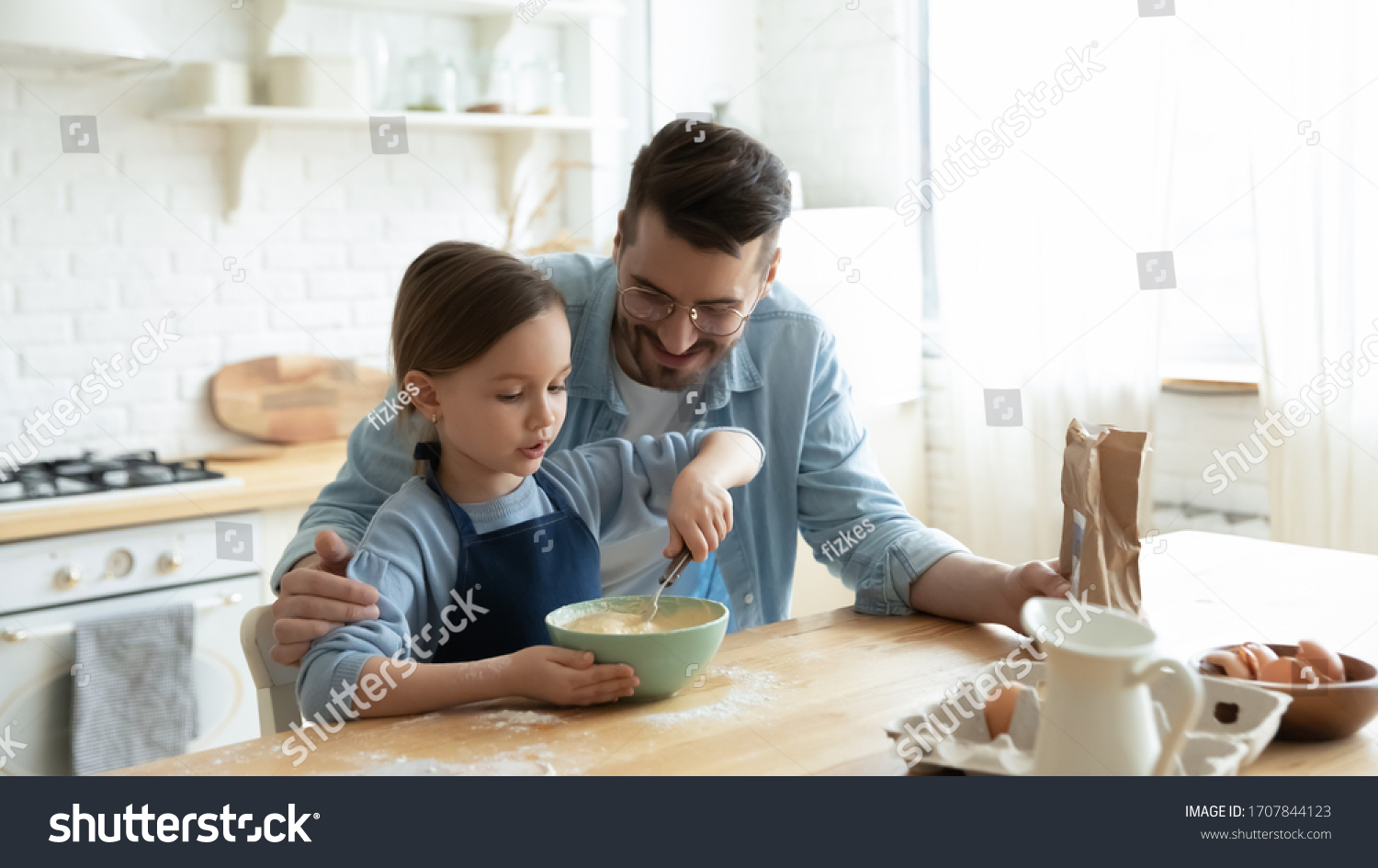 Caring young Caucasian dad and cute little preschooler daughter cooking in modern kitchen together, happy father and small girl child bake cookies pie, preparing pancakes for breakfast at home #1707844123