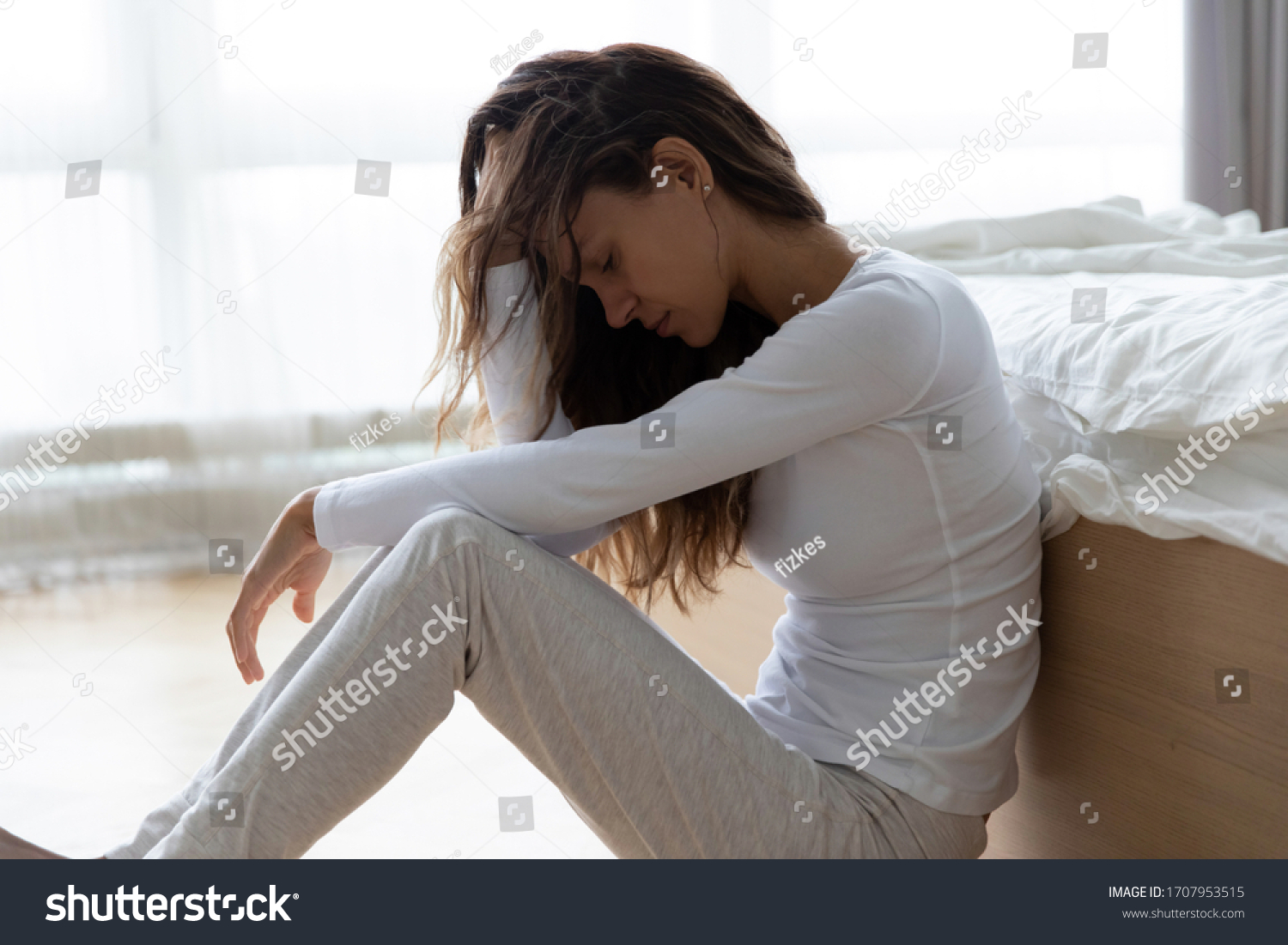 Unhappy woman touching hair, sitting on floor at home, thinking about problems, upset girl feeling lonely and sad, psychological and mental troubles, suffering from bad relationship or break up #1707953515