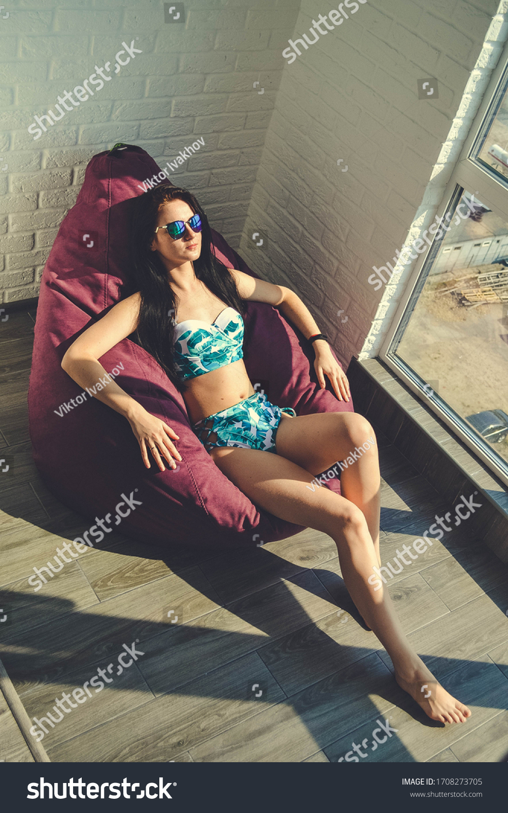 Sunbathing on the balcony. Vacation 2020. During quarantine due to the coronavirus pandemic, the girl stays at home and sunbathes on the balcony. Pretty young woman relax and sunbathing on the balcony #1708273705