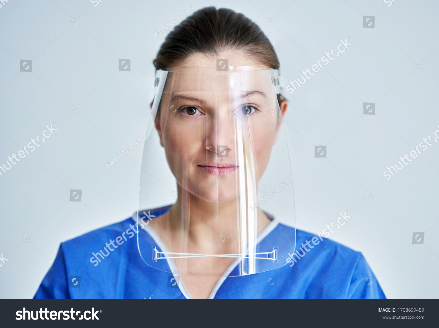 Close up portrait of female medical doctor or nurse wearing face shield #1708699459