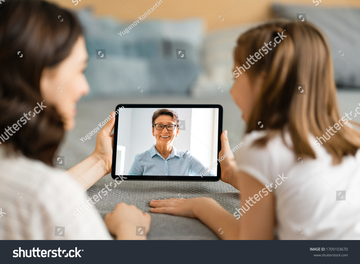 Happy loving family. Young mother and daughter girl using tablet pc for remote conversation with grandma. Funny mom and lovely child are having fun staying at home. #1709103670