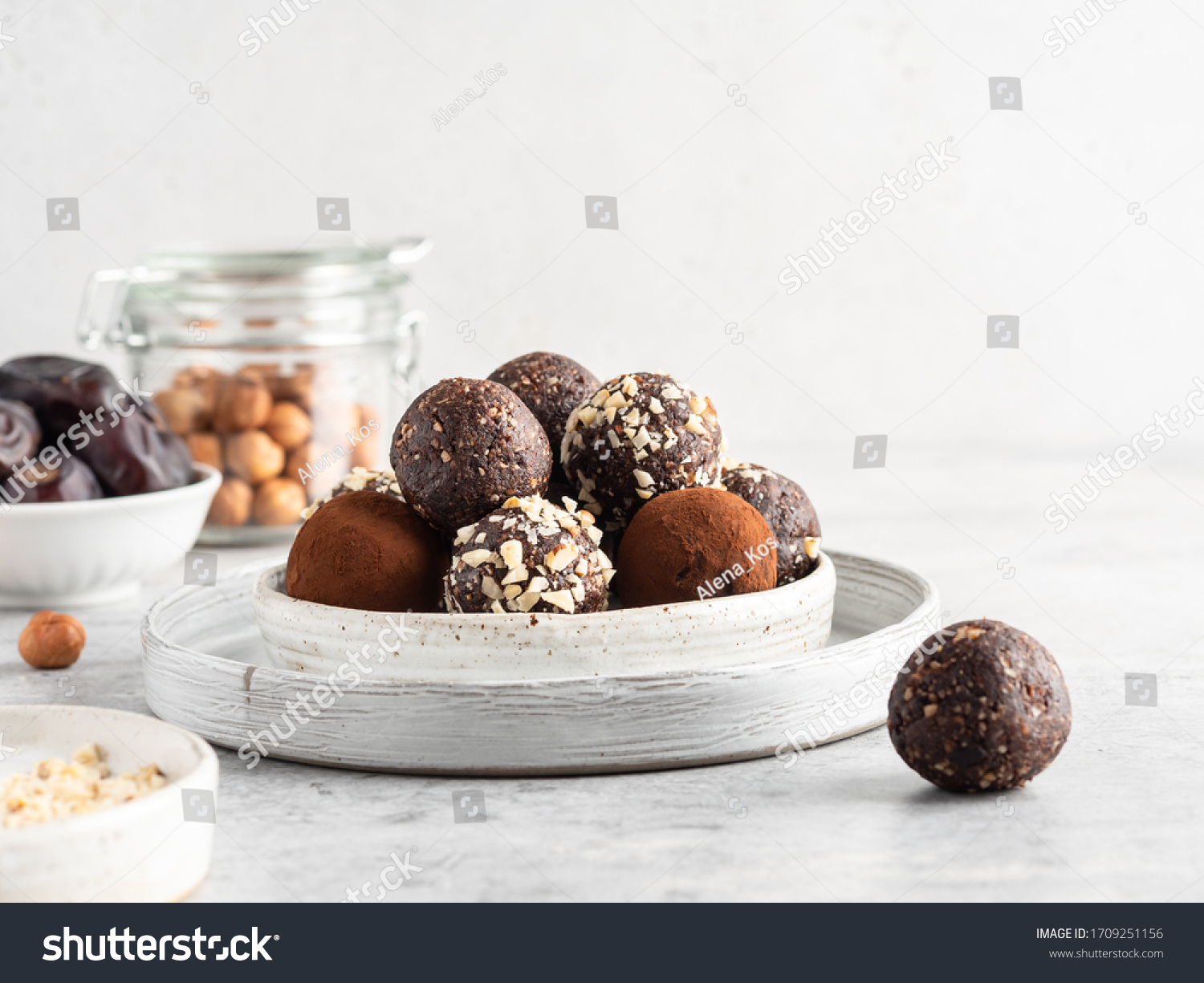 Energy balls. Healthy raw dessert (bliss balls), vegetarian truffles, sugar free candies made of dates, hazelnuts, cocoa powder. Step by step cooking. White wooden background.  #1709251156