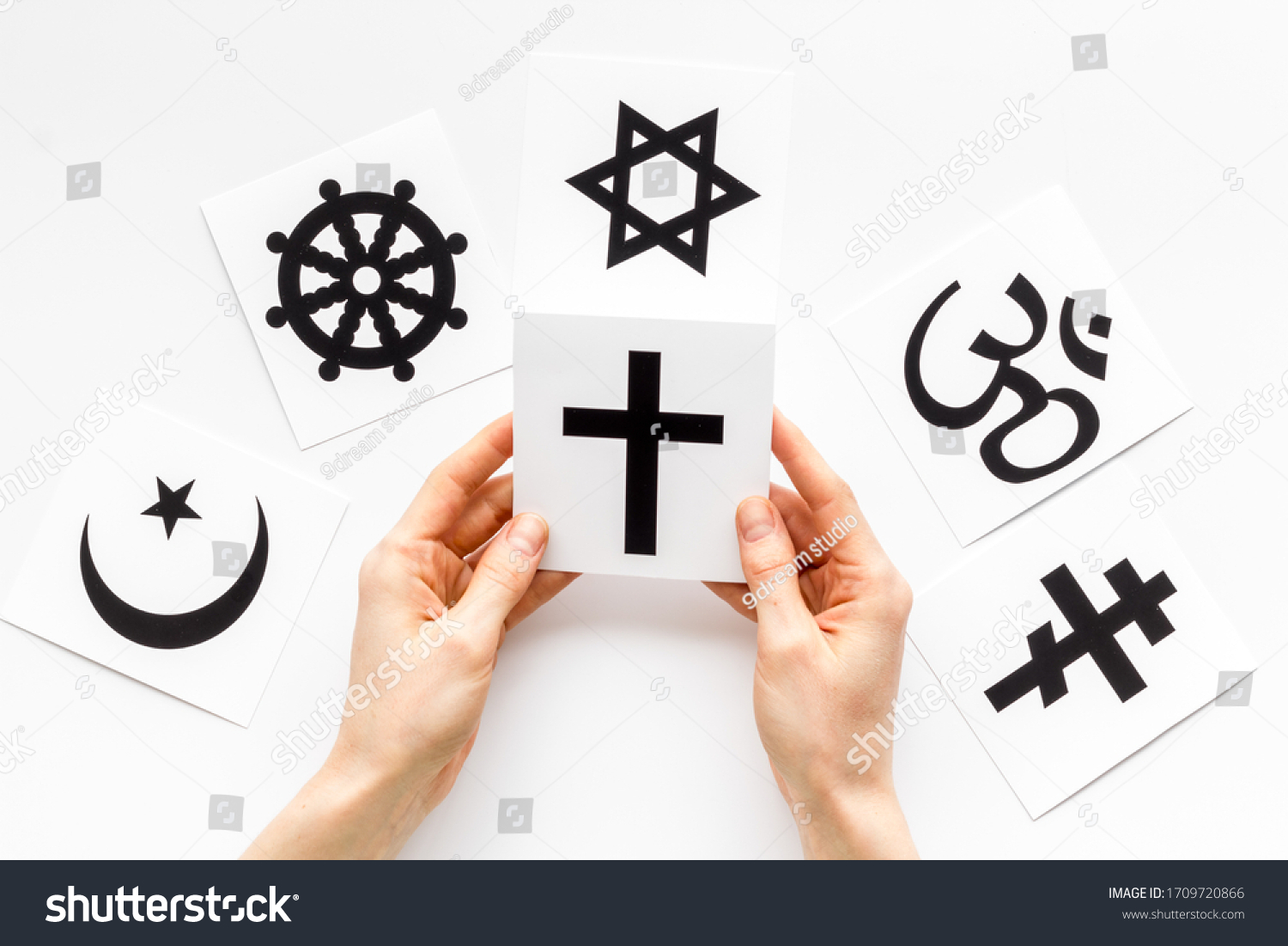 Choose religion concept. Hand with catholic cross near world religions symbols on white background top view #1709720866