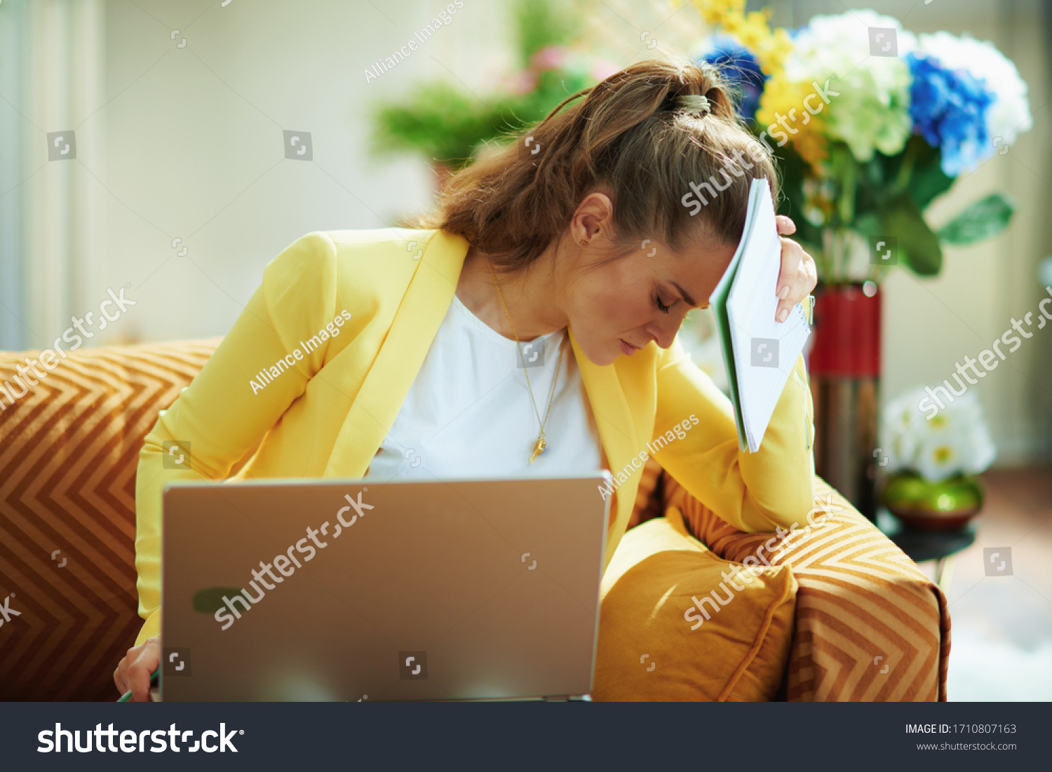 stressed young student in jeans and yellow jacket at modern home in sunny day study online on a laptop. #1710807163