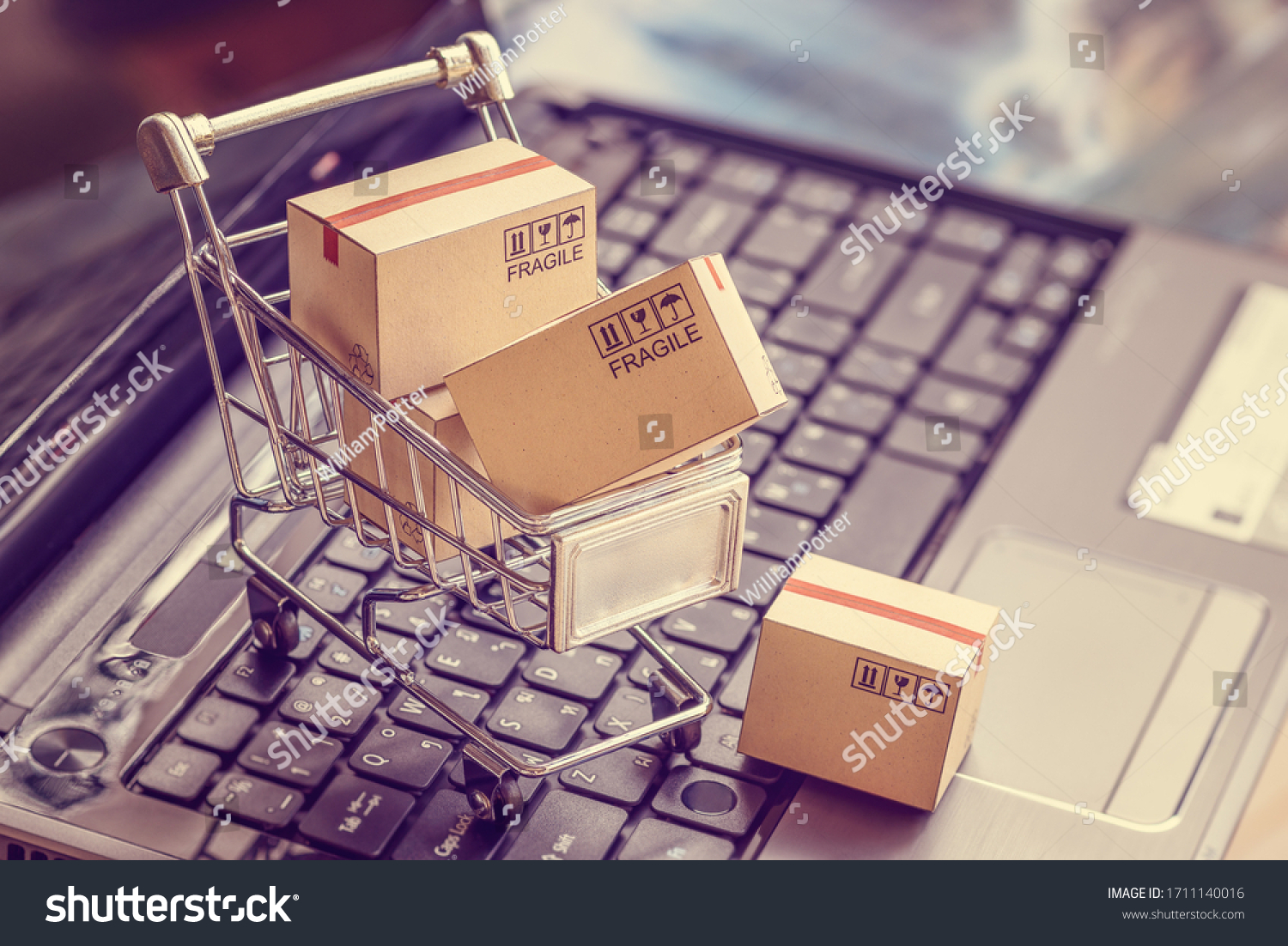 Online shopping  e-commerce and customer experience concept : Boxes with shopping cart on a laptop computer keyboard, depicts consumers  buyers buy or purchase goods and service from home or office #1711140016