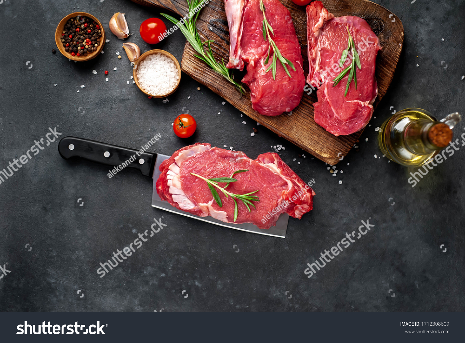 
raw three beef steaks on a cutting board with spices on a stone background #1712308609