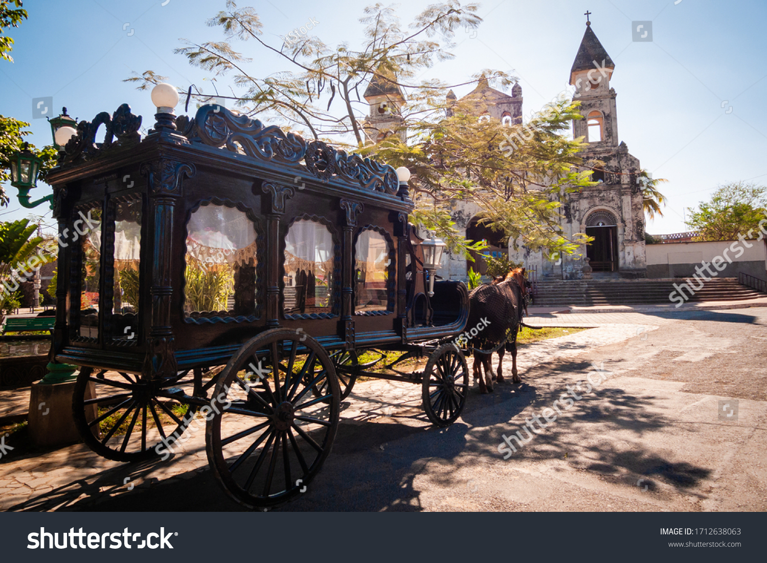 Funeral carriage with horse in front of old church, old horse carriage to carry coffins #1712638063