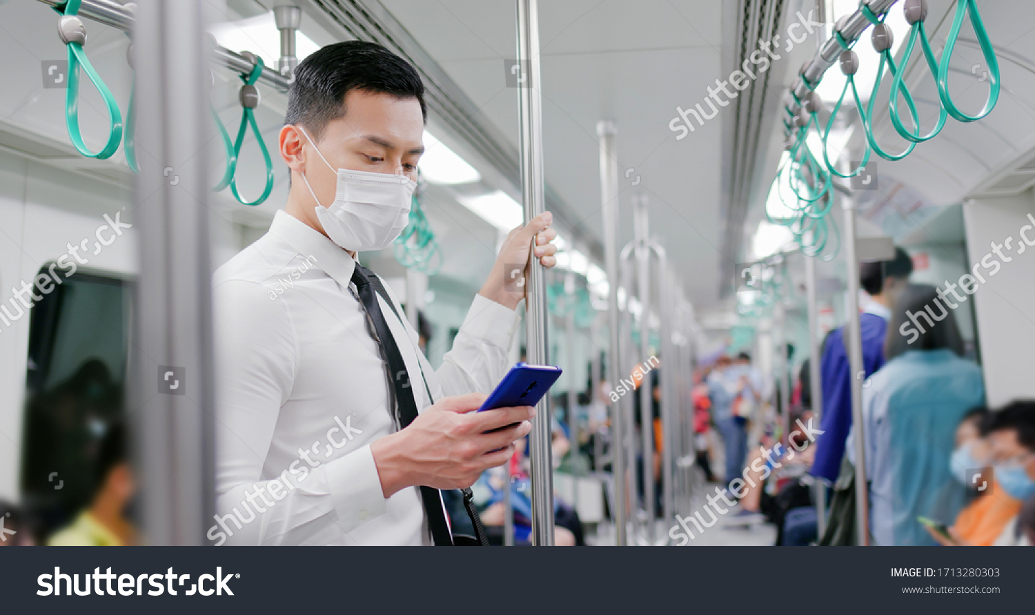Asian business man with surgical mask face protection use a smartphone  and keep social distancing to crowd while commuting in the metro or train #1713280303