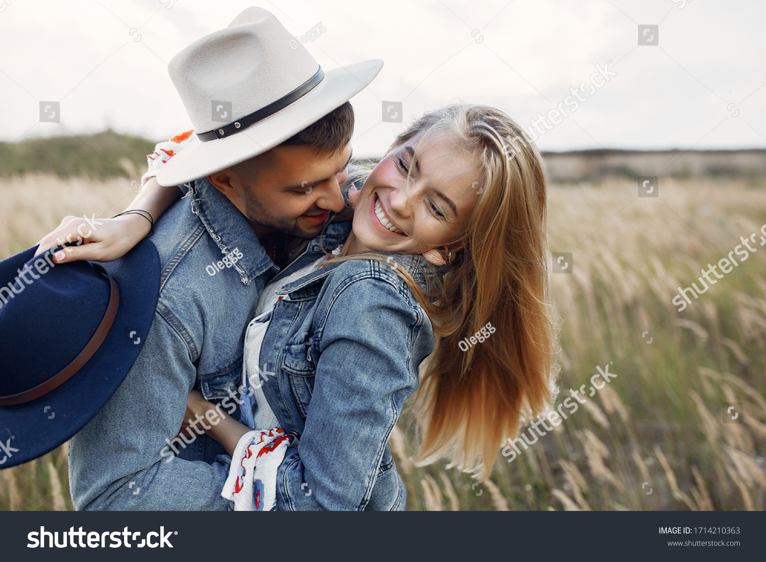 Loving couple in a wheat field. Beautiful blonde in a blue hat. #1714210363