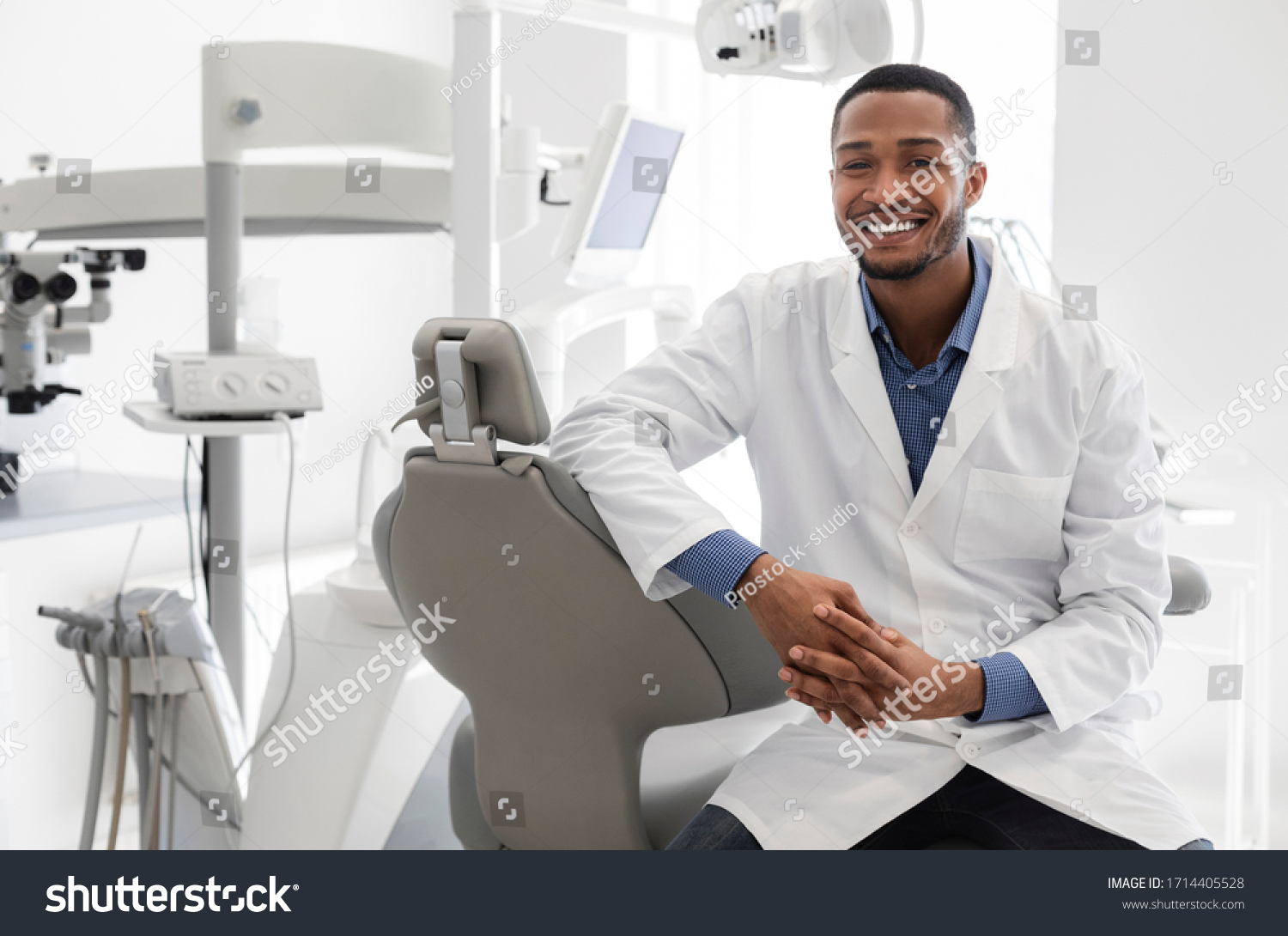 Highly qualified young black dentist posing at clinic over modern cabinet, empty space #1714405528
