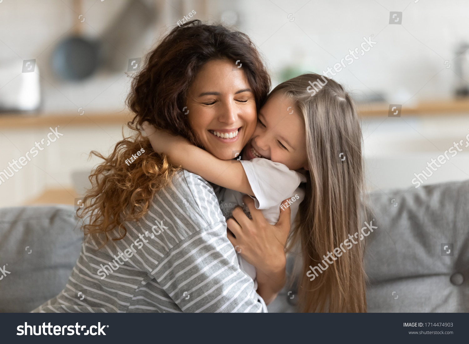 Affectionate beautiful young woman cuddling small preschool child daughter, feeling happiness. Cute little kid girl embracing loving mommy, feeling thankful, enjoying tender sweet time at home. #1714474903