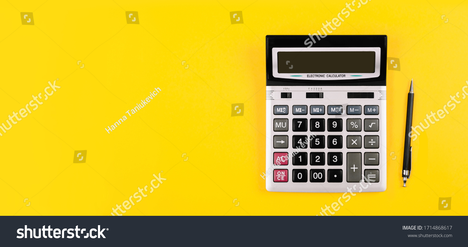 Large silver calculator with gray and black buttons and black pen on a yellow background. Conceptual photo of calculations, accounting, computing, profit, loss, tax with place for text. #1714868617
