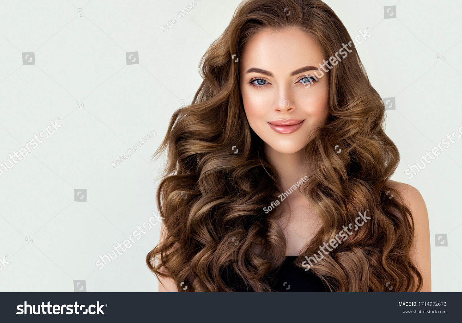 Beautiful laughing brunette model  girl  with long curly  hair . Smiling  woman hairstyle wavy curls . Red  nails manicure .    Fashion , beauty and makeup portrait
