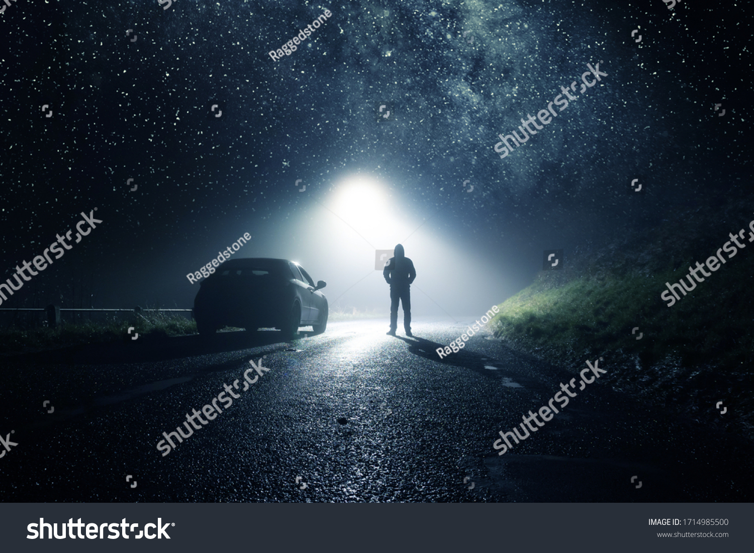 A lone car, parked on the side of the road with a hooded figure, on a spooky country road. With a bright light and stars at night. #1714985500