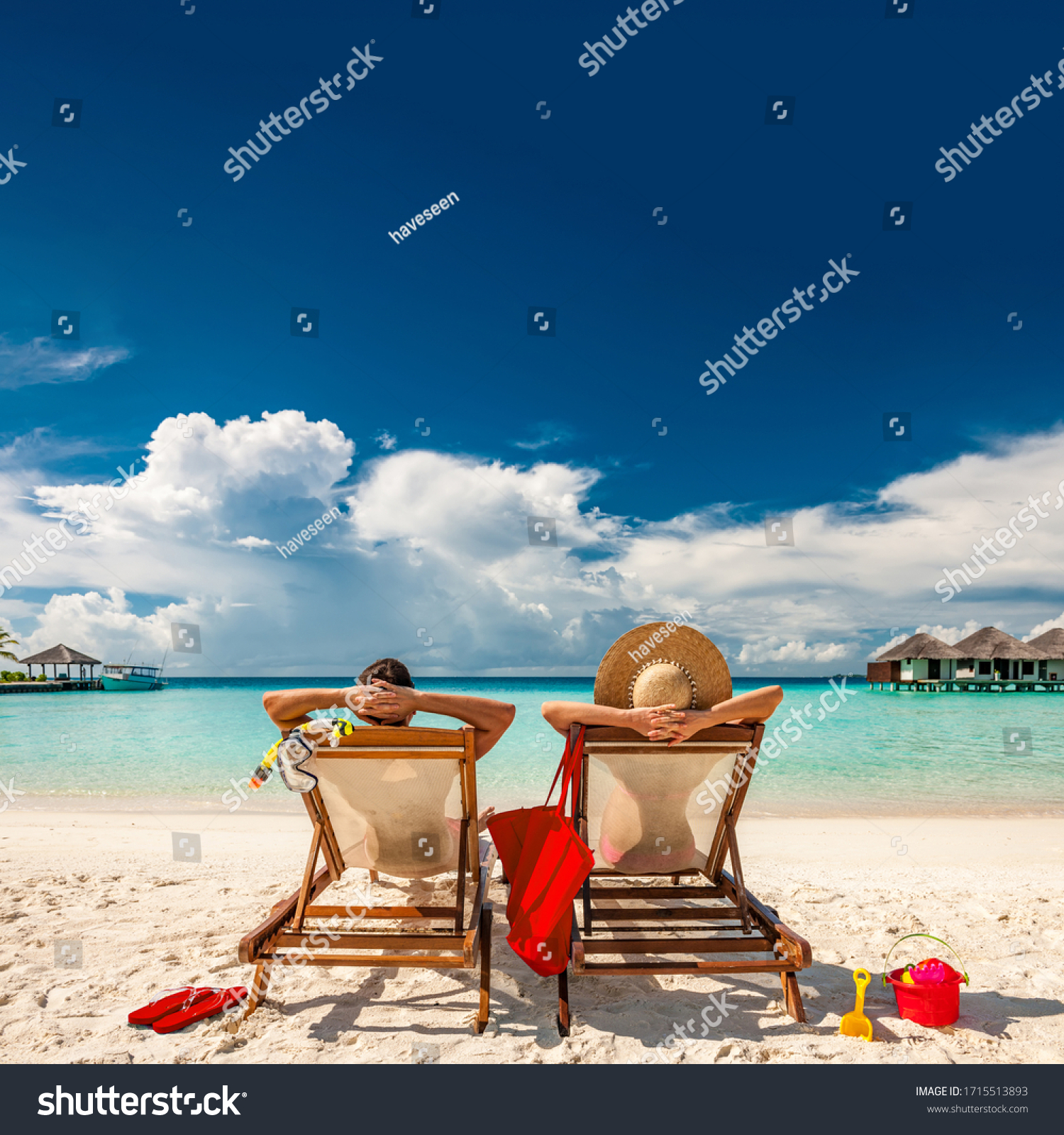 Couple in loungers on a tropical beach at Maldives #1715513893