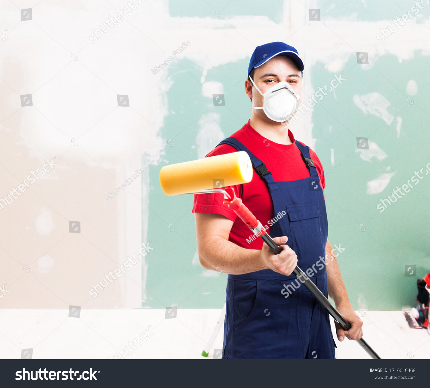 Portrait of a masked painter at work in an apartment, renovation and home painting during coronavirus pandemic #1716010468
