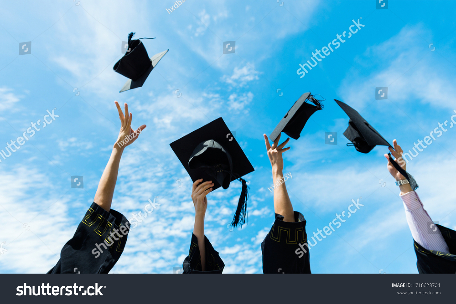 Four graduates throwing graduation hats in the air. #1716623704