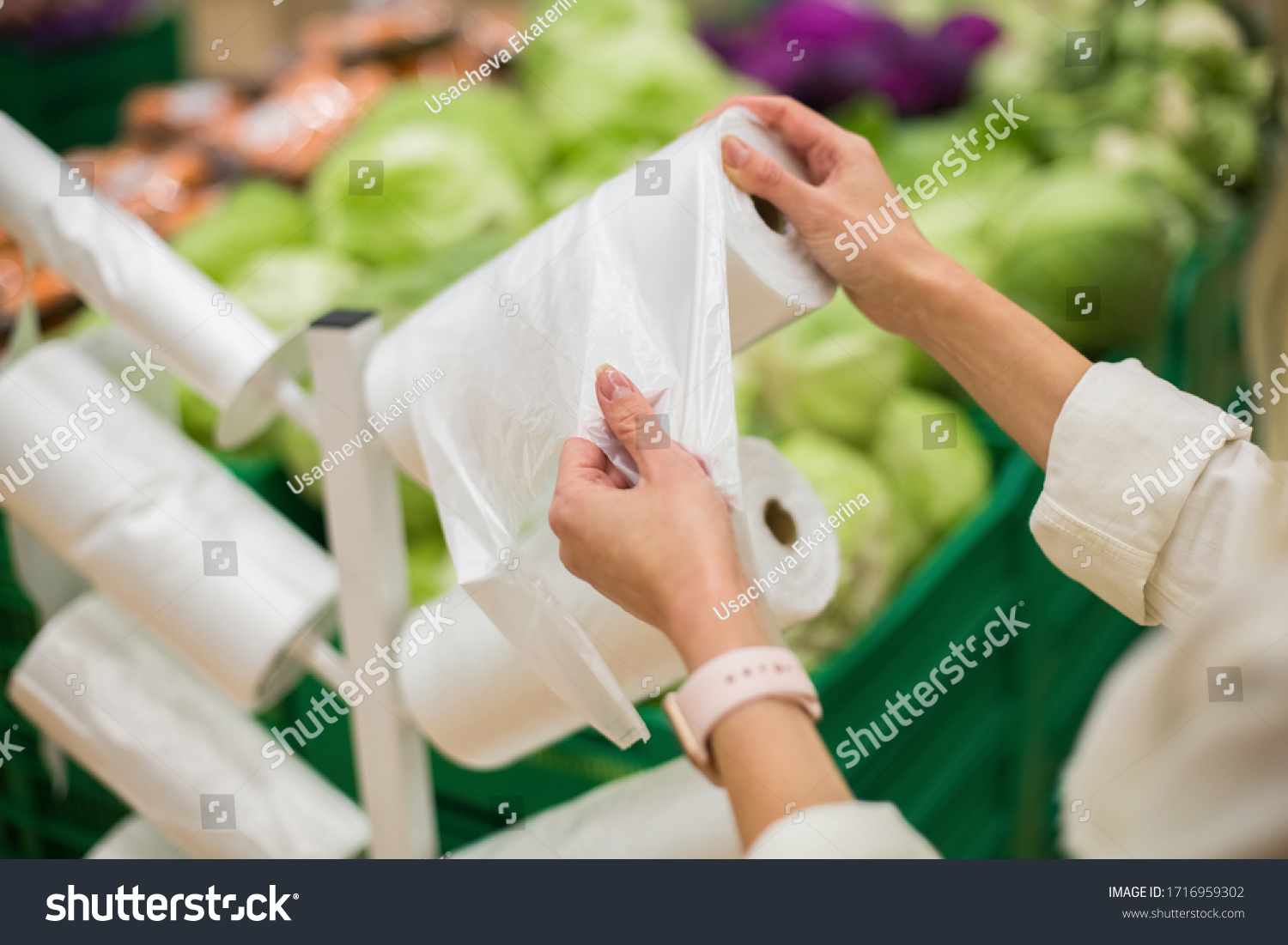 Adult woman taking one plastic package from the roll of packing plastic bags in the vegetable department of the supermarket or grocery store #1716959302