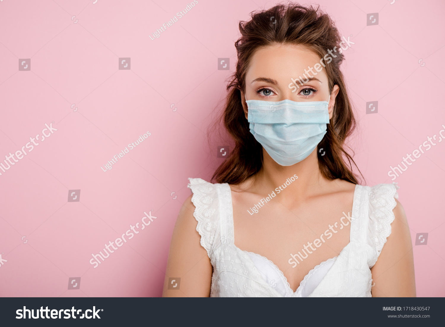 young woman in medical mask standing on pink #1718430547