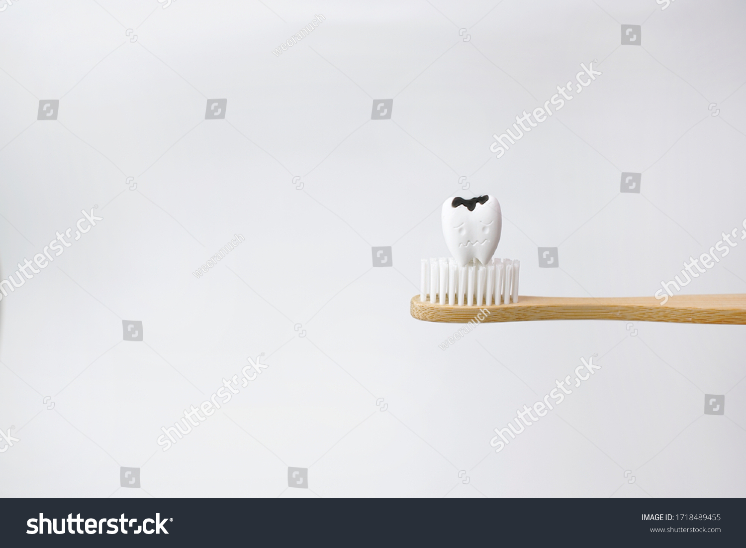 Cavity decayed tooth on wooden brown toothbrush on white background, How to prevent tooth decay and cavities #1718489455