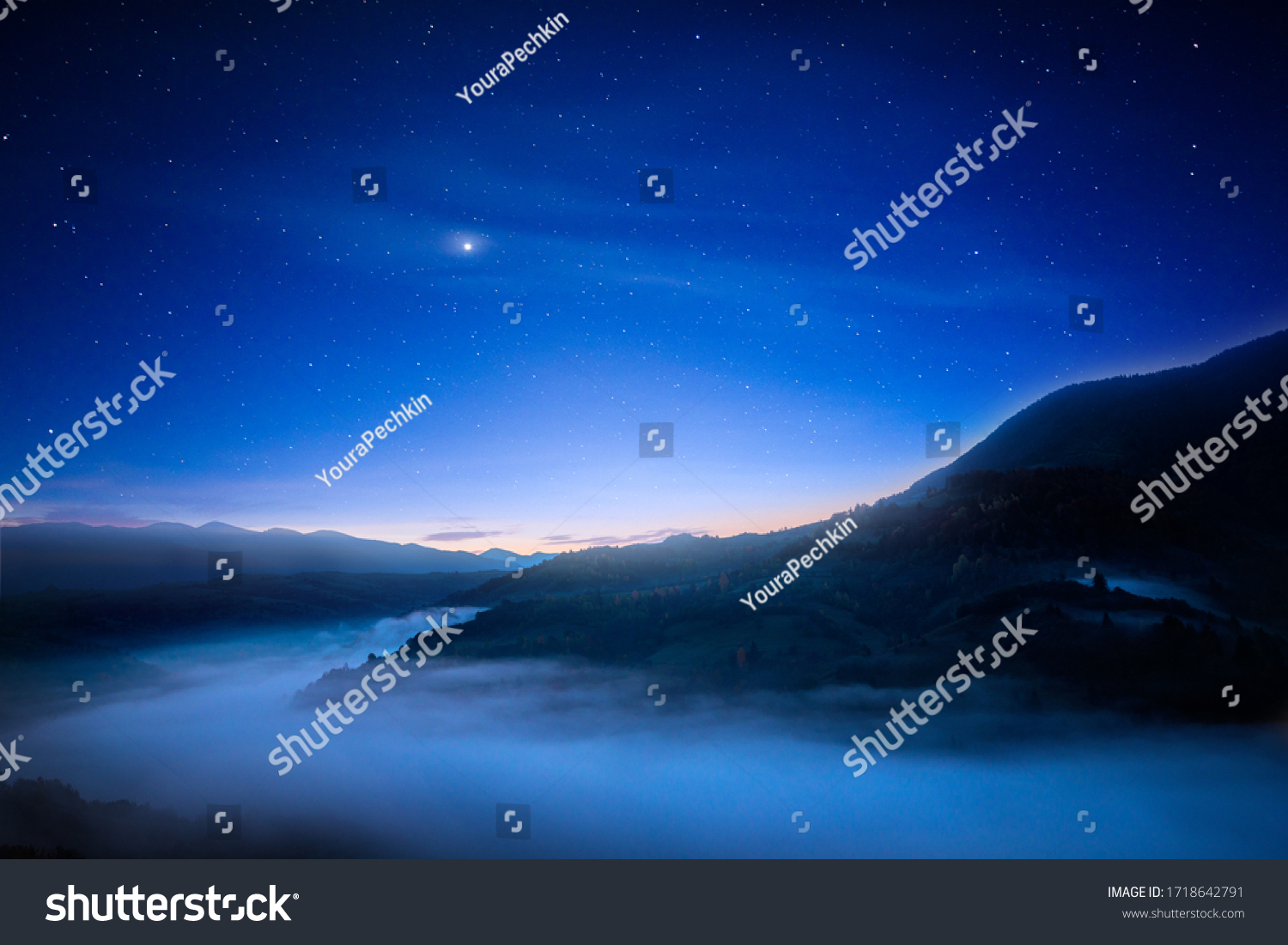 View of beautiful night sky with stars in foggy mountain valley. Scenic landscape of misty hills under blue starry sky. Concept of astrology and magical nighttime. #1718642791