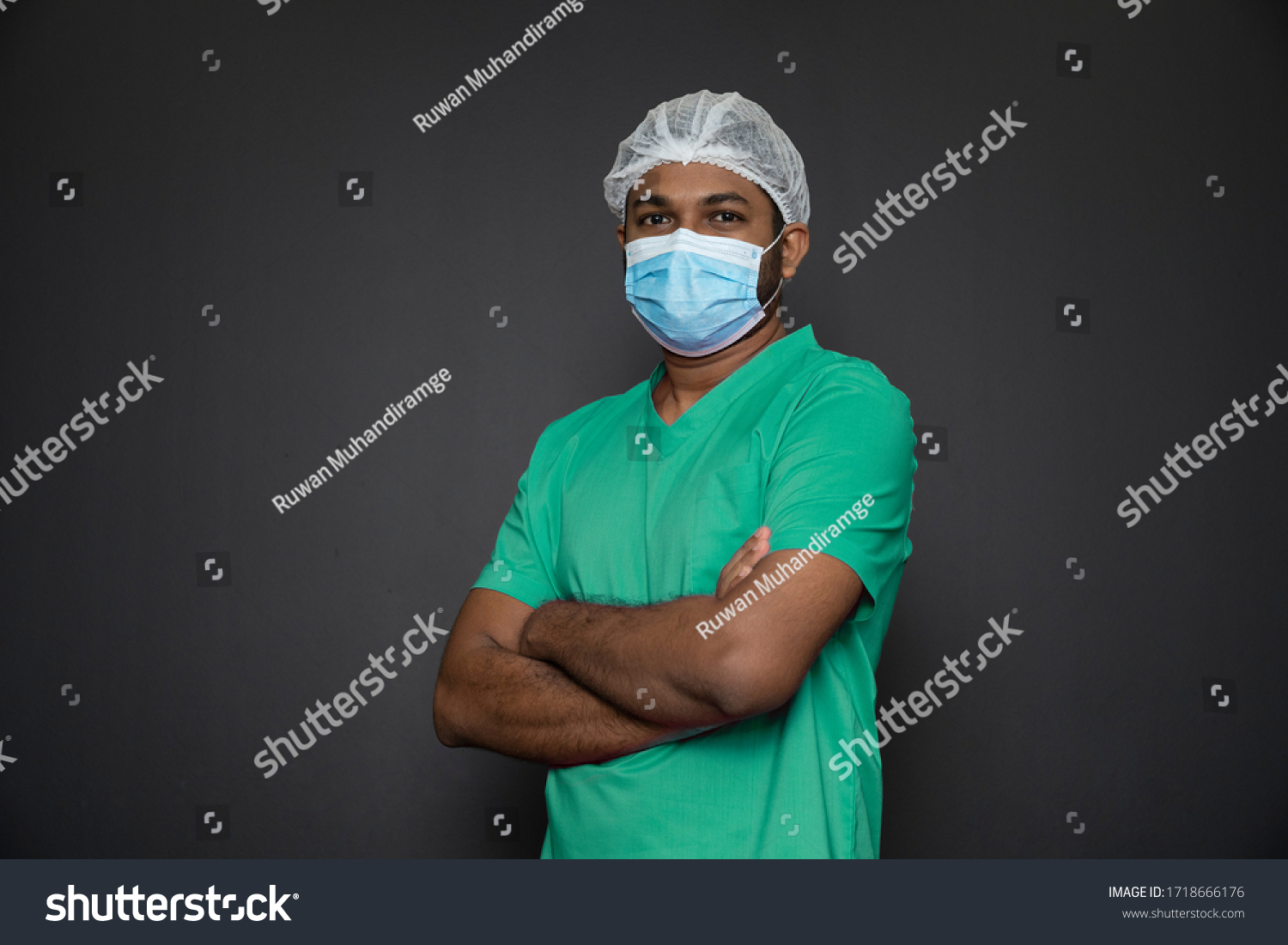 Portrait of a male nurse standing with arms folded isolated on a black background. Asian Nurse looking at camera. Male nurse with protective face mask against corona virus epidemic COVID-19 #1718666176