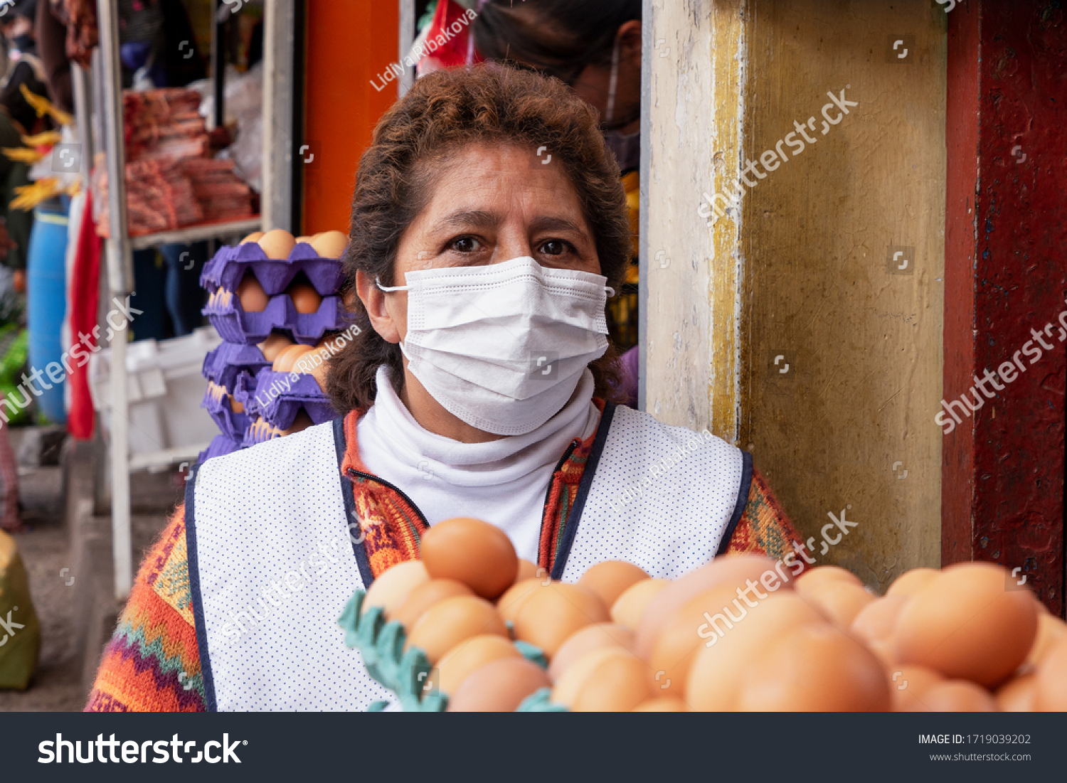 Eggs seller in respiratory mask in the market during coronavirus pandemic in Cusco, Peru in Latin South America. Epidemic of coronavirus covid-19 #1719039202