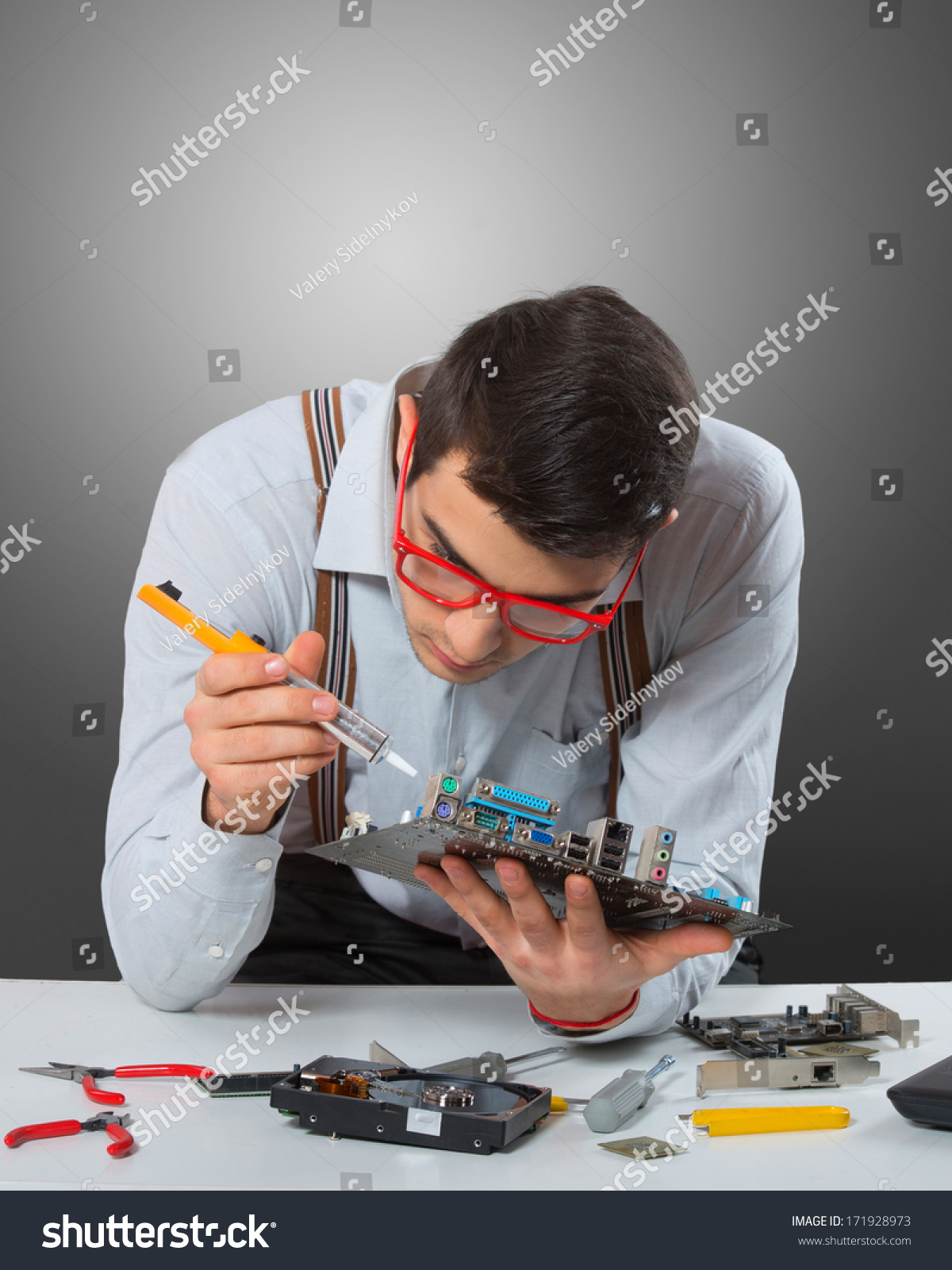 Man in red-framed glasses fixing a computer mother board, gray background #171928973