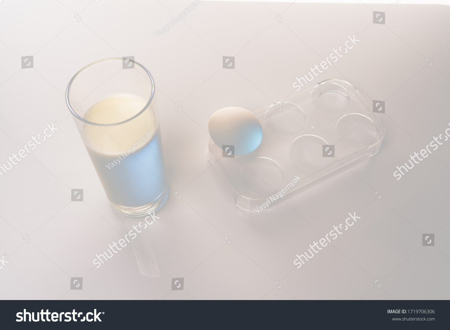 Glass of milk and chicken egg in plastic holder isolated on white background #1719706306