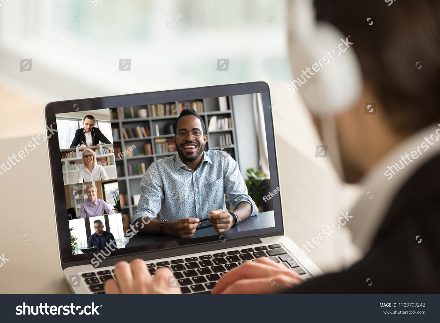 Back view of male employee in headphones have online webcam conference on computer with diverse colleagues, businessman talk speak on video call on laptop from home with multiracial coworkers #1720799242