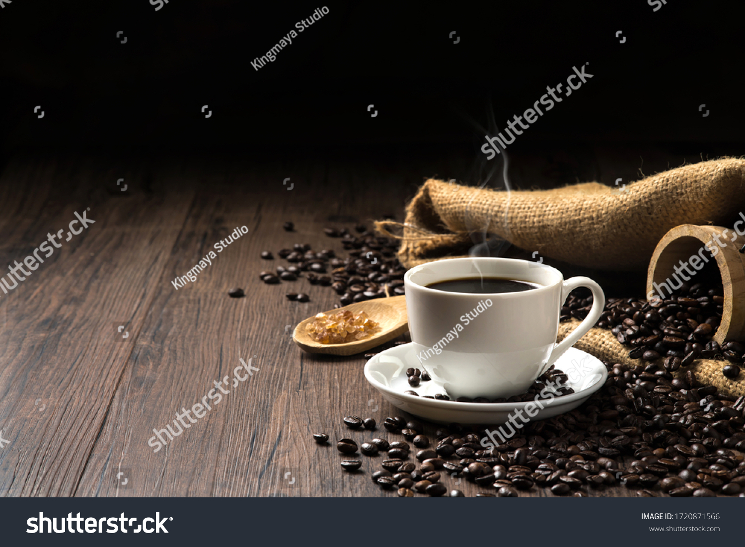 Hot coffee in a white coffee cup and many coffee beans placed around and sugar on a wooden table in a warm, light atmosphere, on dark background, with copy space. #1720871566