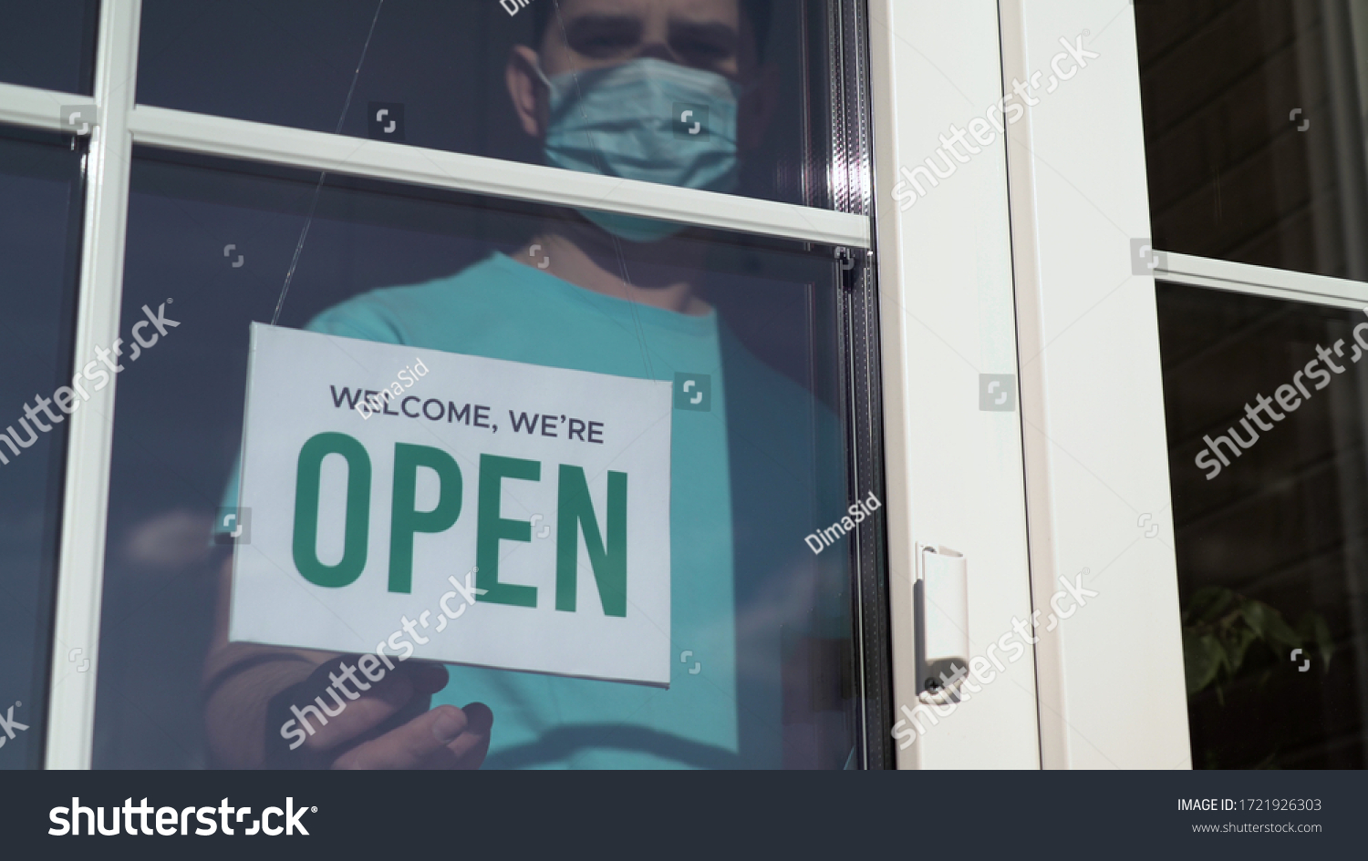 Close up of the male Caucasian hands turning a signboard on the glass door of the shop from CLOSED to OPEN. Reopening of a small business activity after quarantine covid-19 emergency. #1721926303