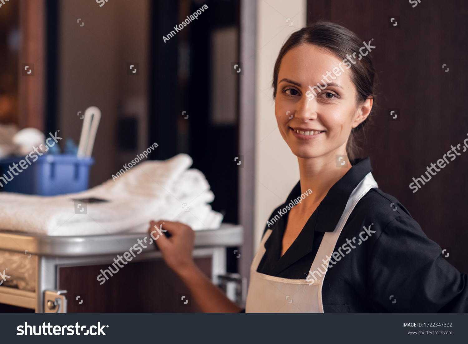 A portrait of a smiling hotel maid with a cleaning cart and clea #1722347302