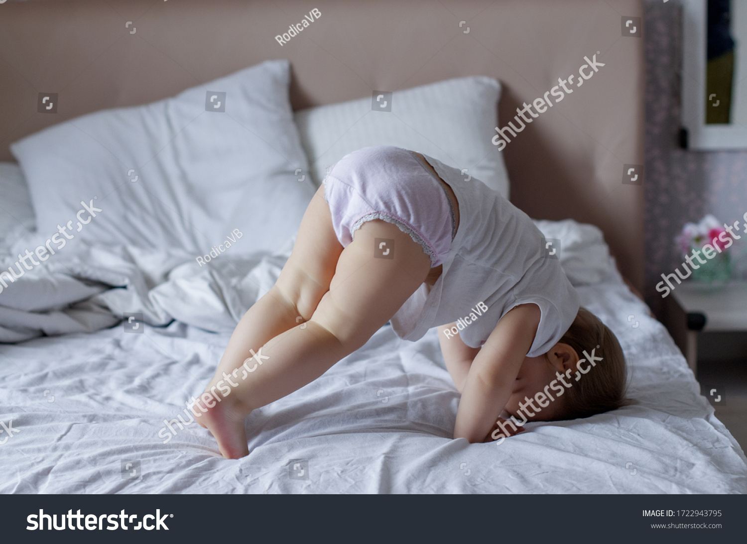Cute adorable baby girl in a white bed. Morning time. Relax time. Baby child playful. Bed time. Playfulness. Happy lovely baby playing in bed #1722943795