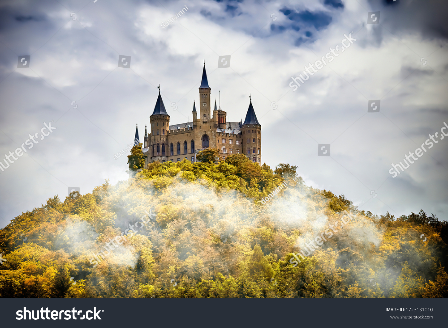 Castle on a wooded mountain in the fog under clouds, Hohenzollern, Germany #1723131010