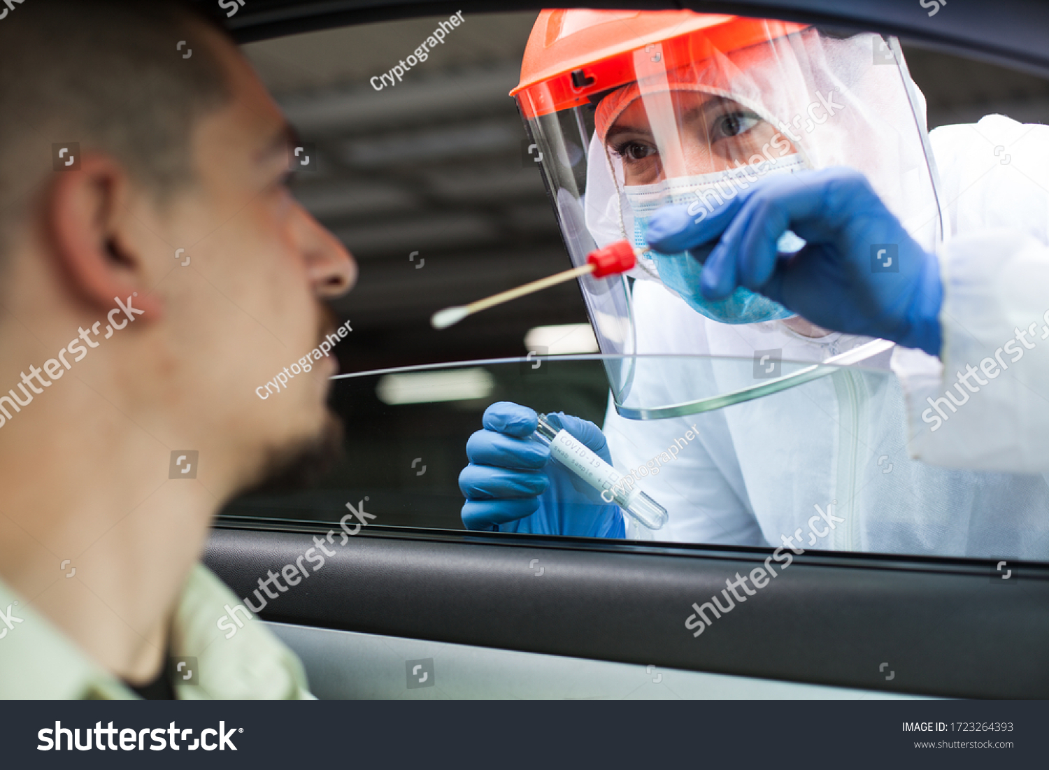Medical NHS UK worker performing drive-thru COVID-19 check,taking nasal swab specimen sample from male patient through car window,PCR diagnostic for Coronavirus presence,doctor in PPE holding test kit #1723264393
