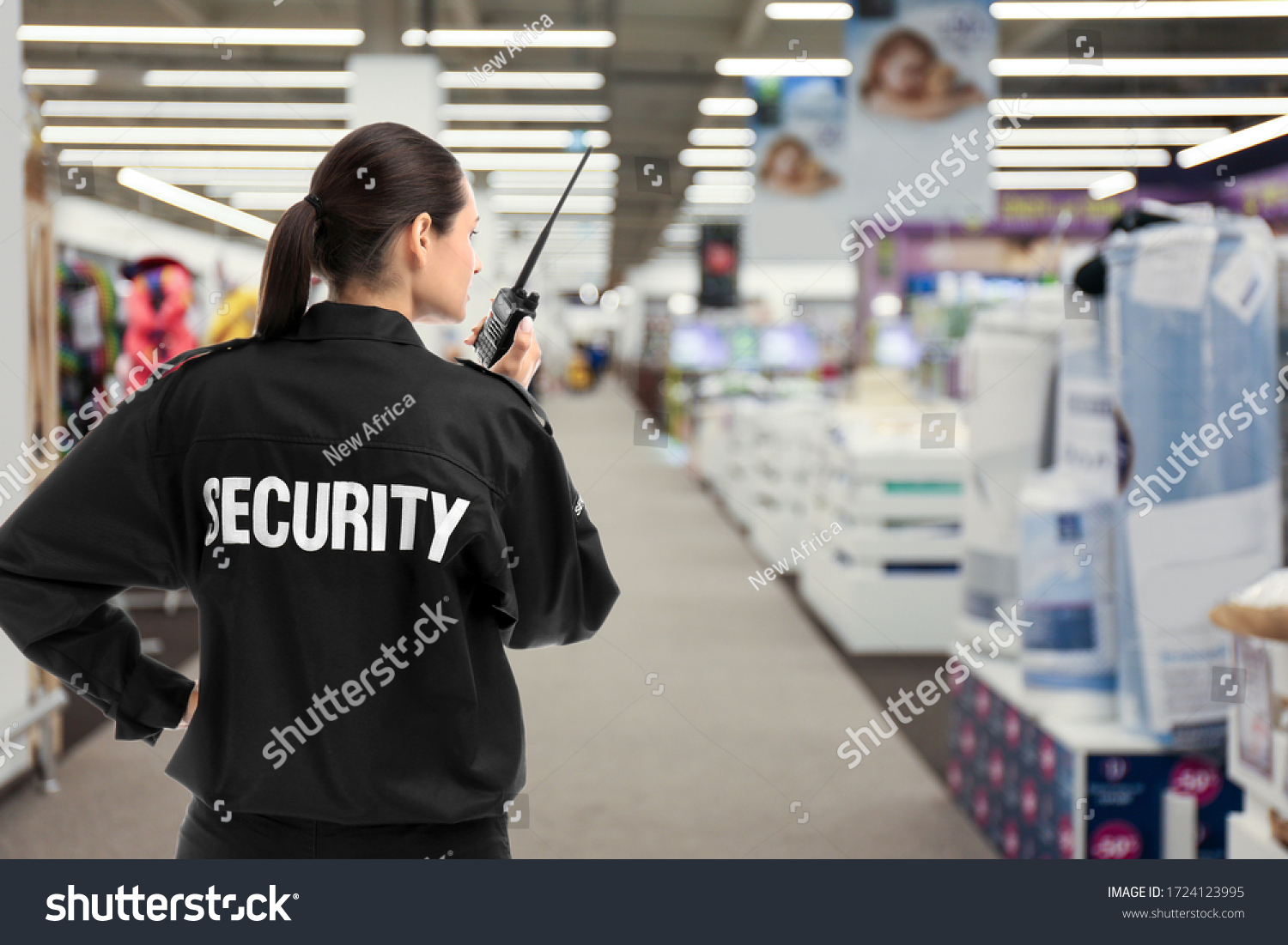 Security guard using portable radio transmitter in shopping mall, space for text #1724123995