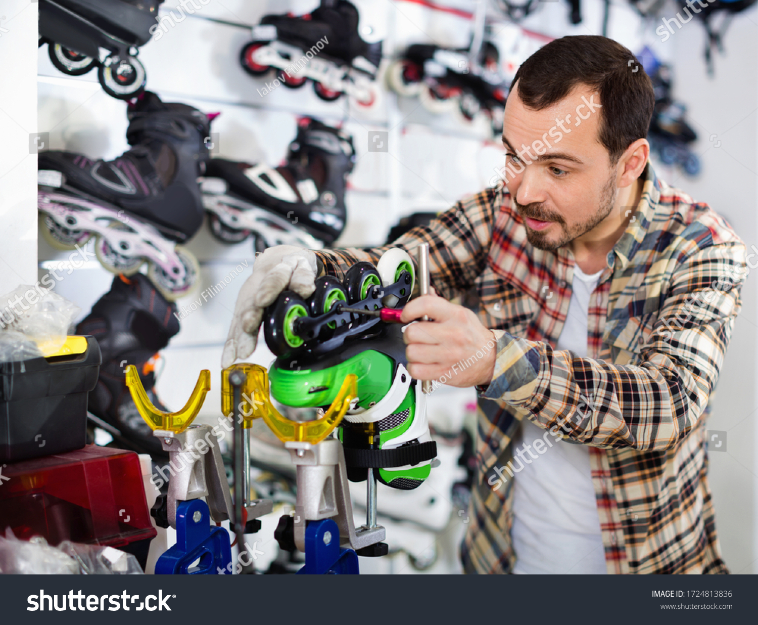 Satisfied  male master fixing roller-skates in sports store #1724813836